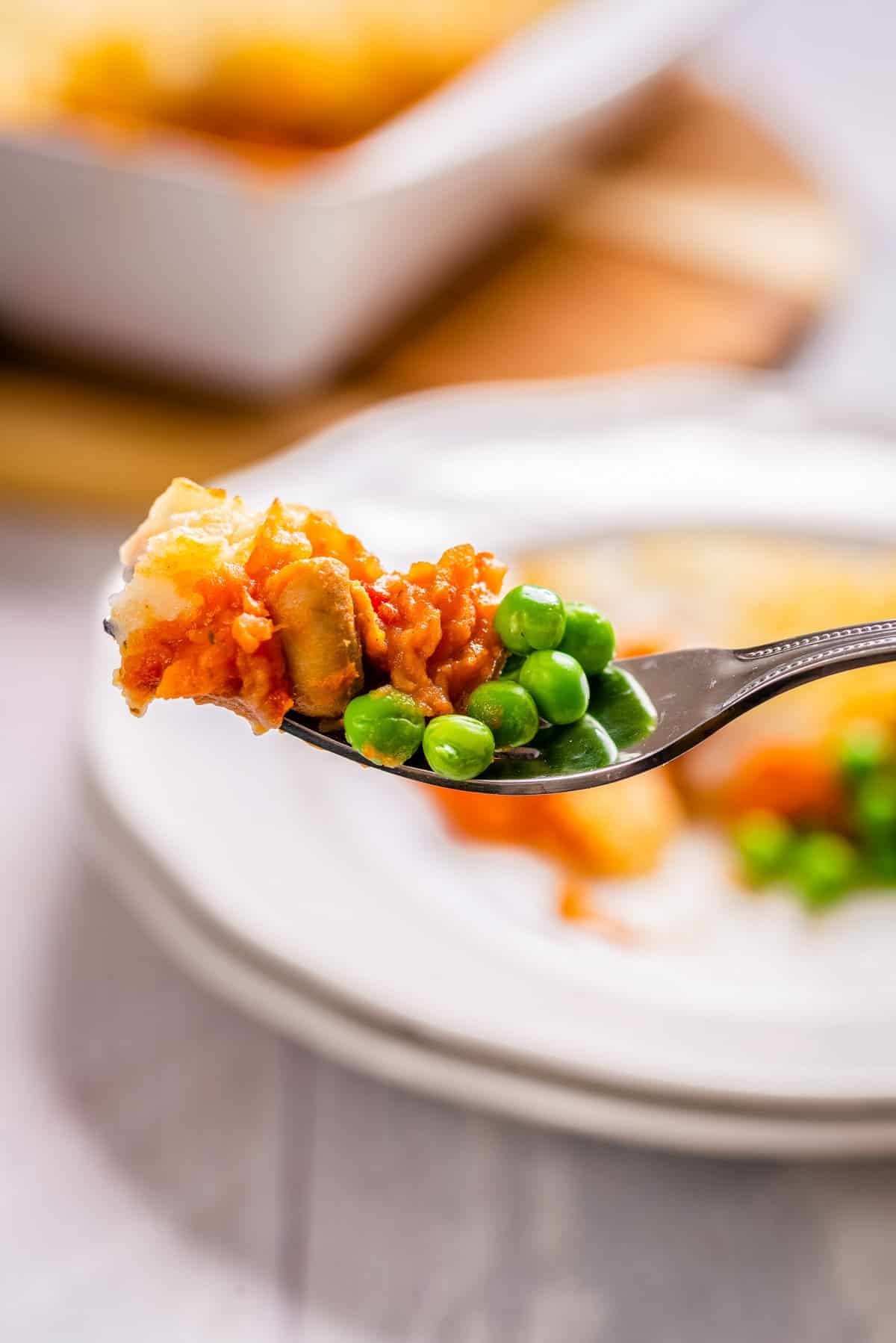 Close up of vegan shepherd's pie with peas, on a fork. 