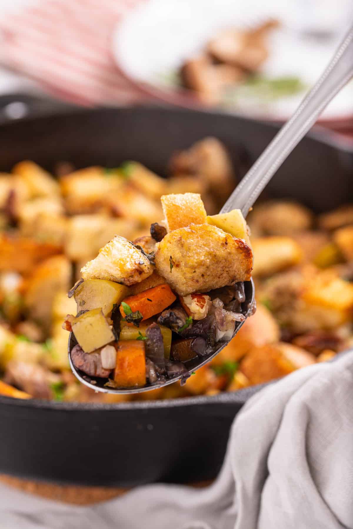 Close up of spoonful of stuffing over the skillet.