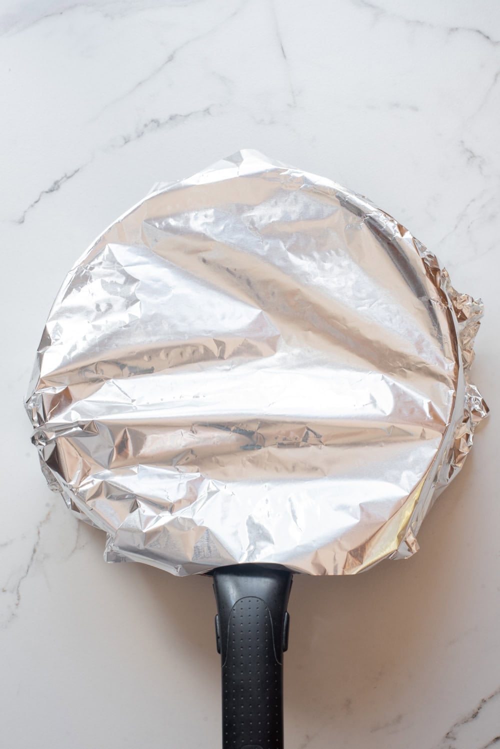 Rice pot sealed with foil and a lid before baking in the oven.