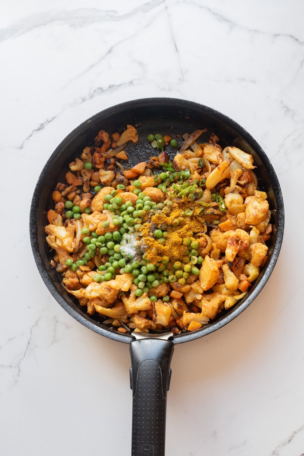 Vegetable mixture with peas and spices cooking for vegetable biryani.