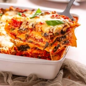 An image of a slice of vegetable lasagna being scooped out of the baking dish.