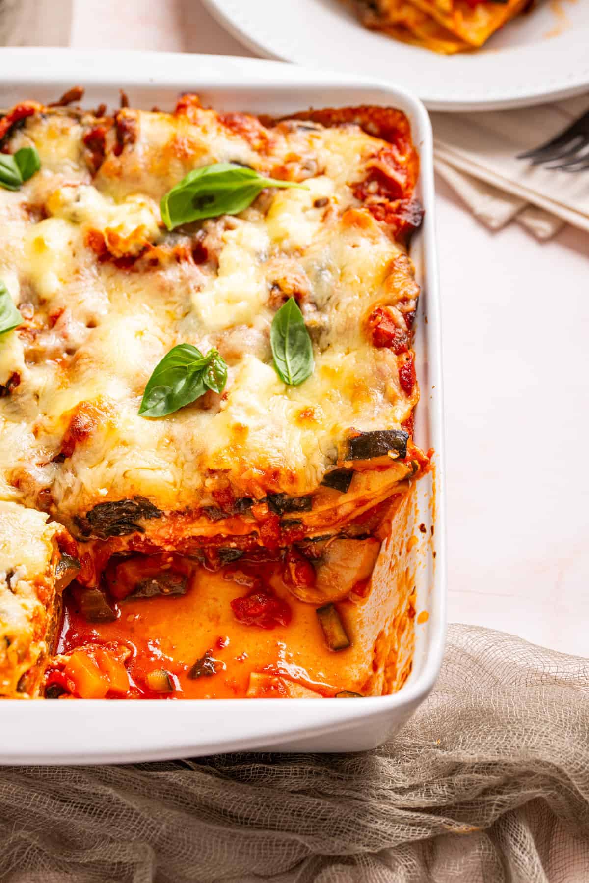 A close up image of baked vegetable lasagna with one slice taken out of the baking dish.
