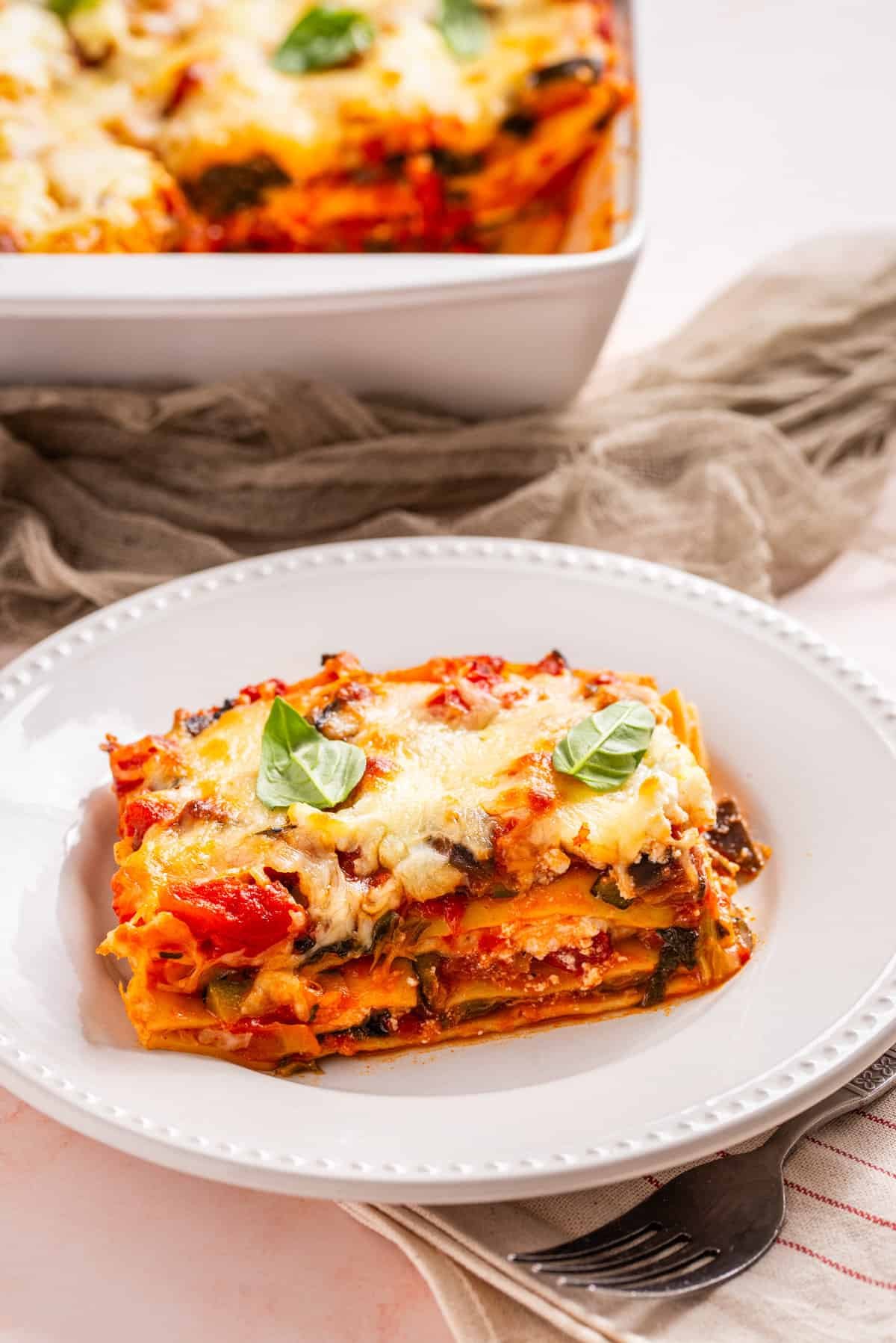An image of a slice of vegetable lasagna in a white serving dish.