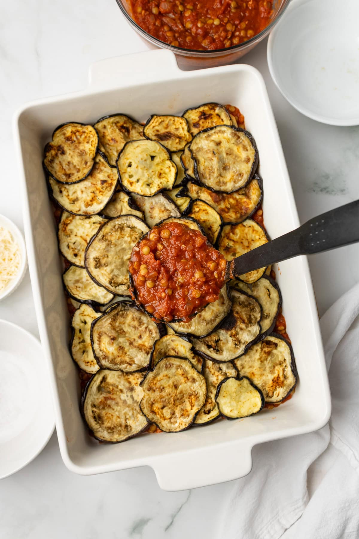 An overhead image of layering the eggplants and potato slices on the baking dish.