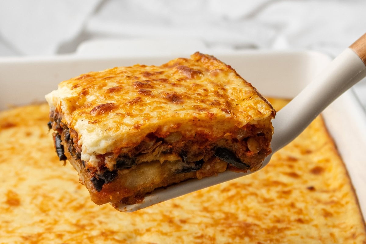 A close up image of a portion of vegetarian moussaka lifted up on a spatula.