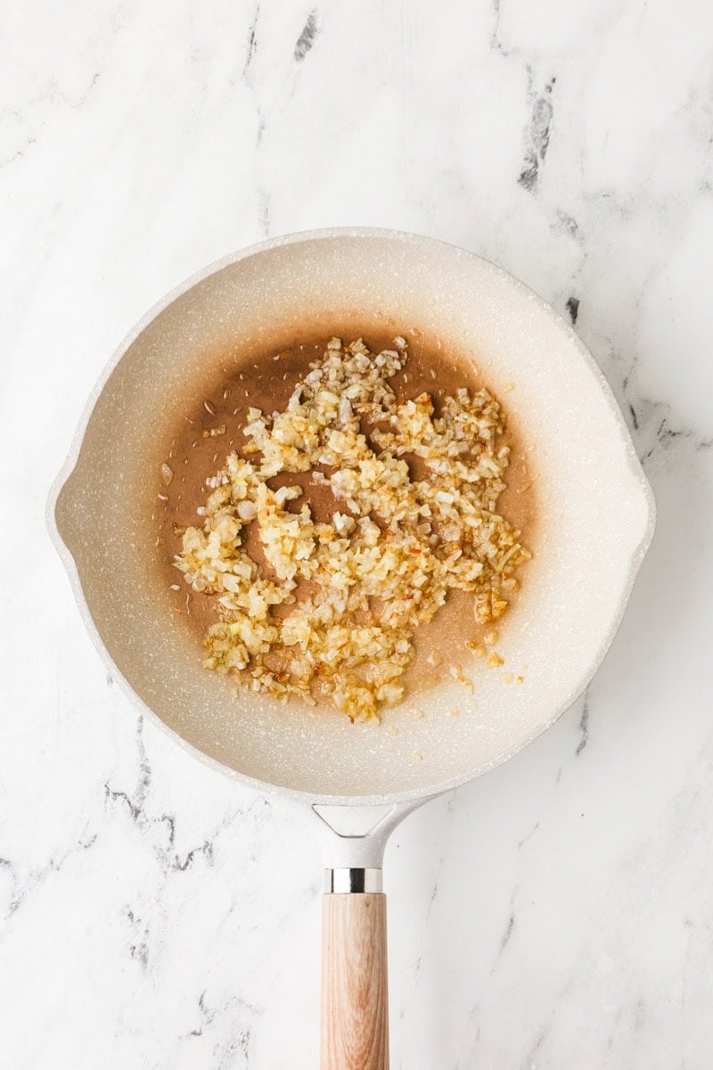 Caramelizing diced onion in a skillet until golden and jammy.
