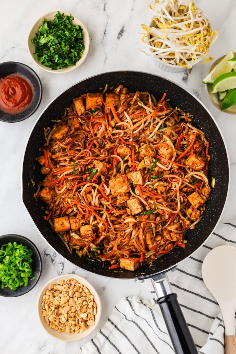 Finished tofu pad thai in skillet with peanuts, herbs, and lime.