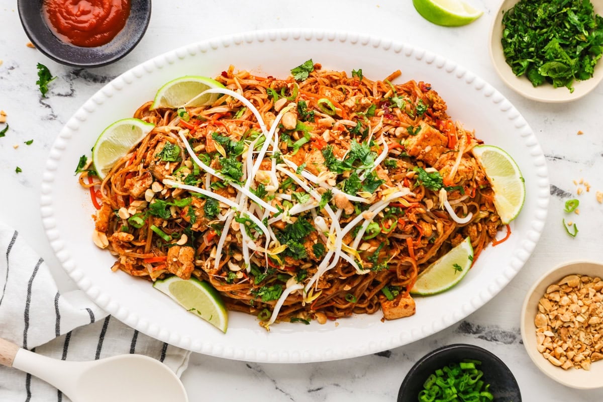Plated tofu pad thai without tamarind topped with peanuts, cilantro, and fresh bean sprouts.