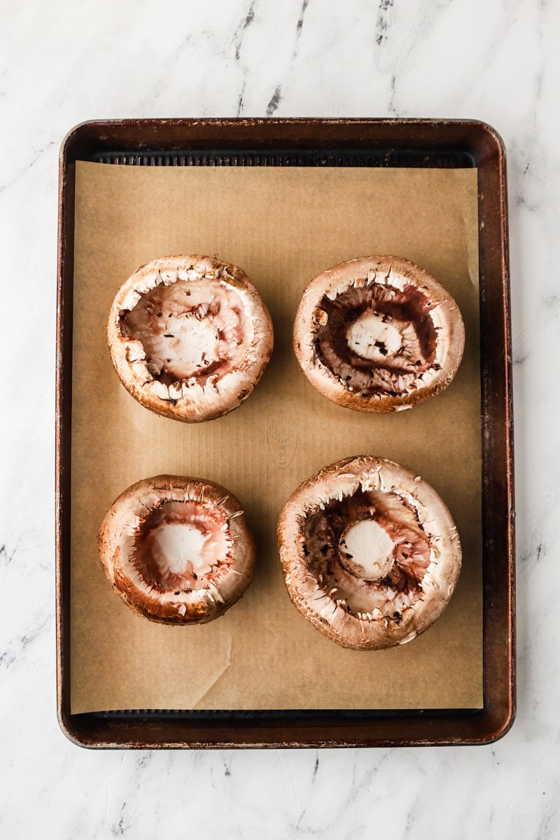 An overhead image of portobello mushrooms on a baking sheet.