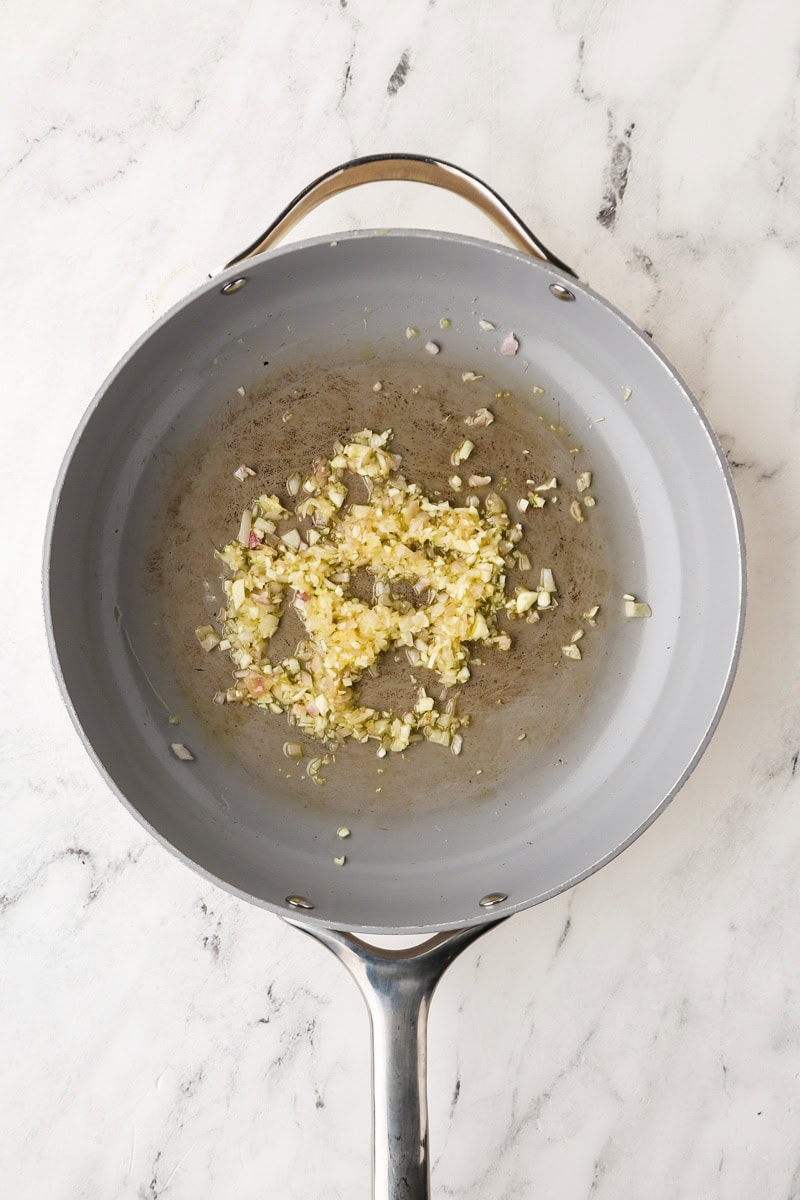 An overhead image of sauteing garlic in a skillet.
