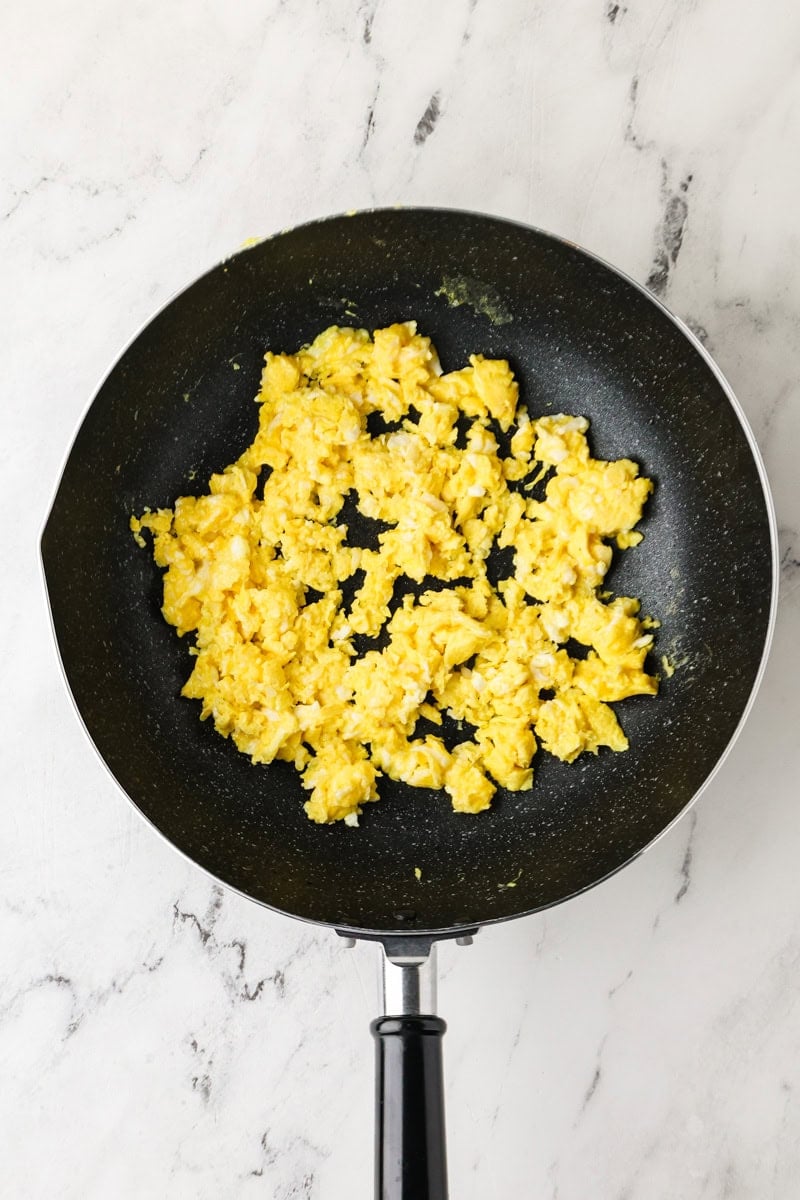 Scrambled eggs cooking in a skillet for Thai fried rice.