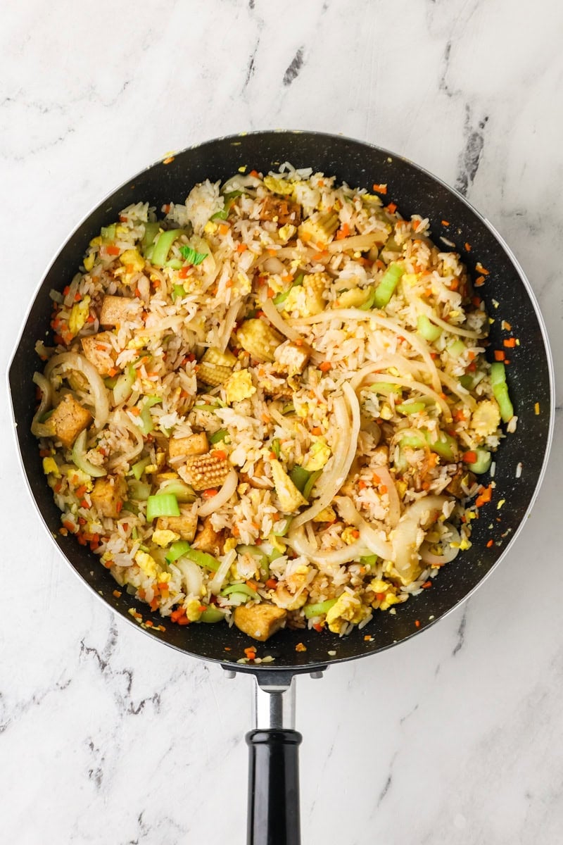 Jasmine rice and tofu tossed together with vegetables and sauce in a skillet.
