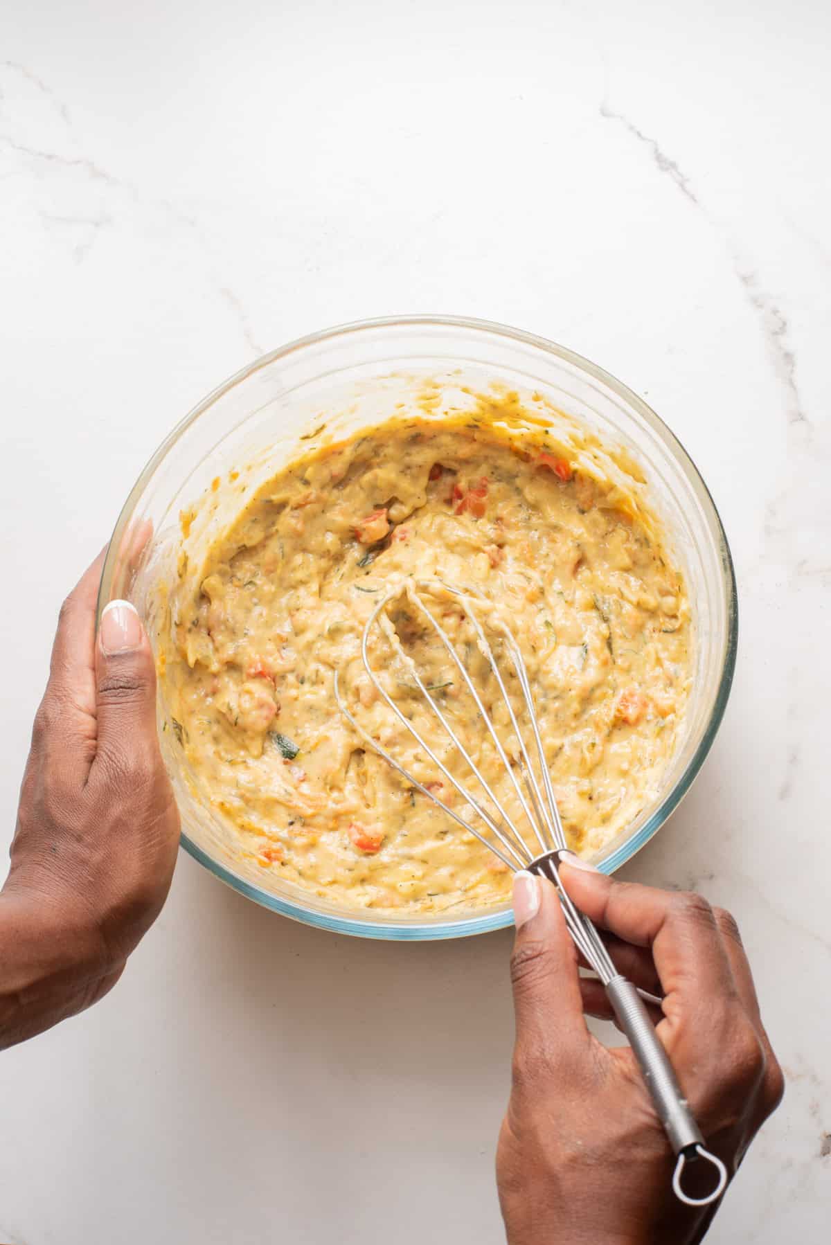 An overhead image of whisking the veggie muffin batter together in a bowl.