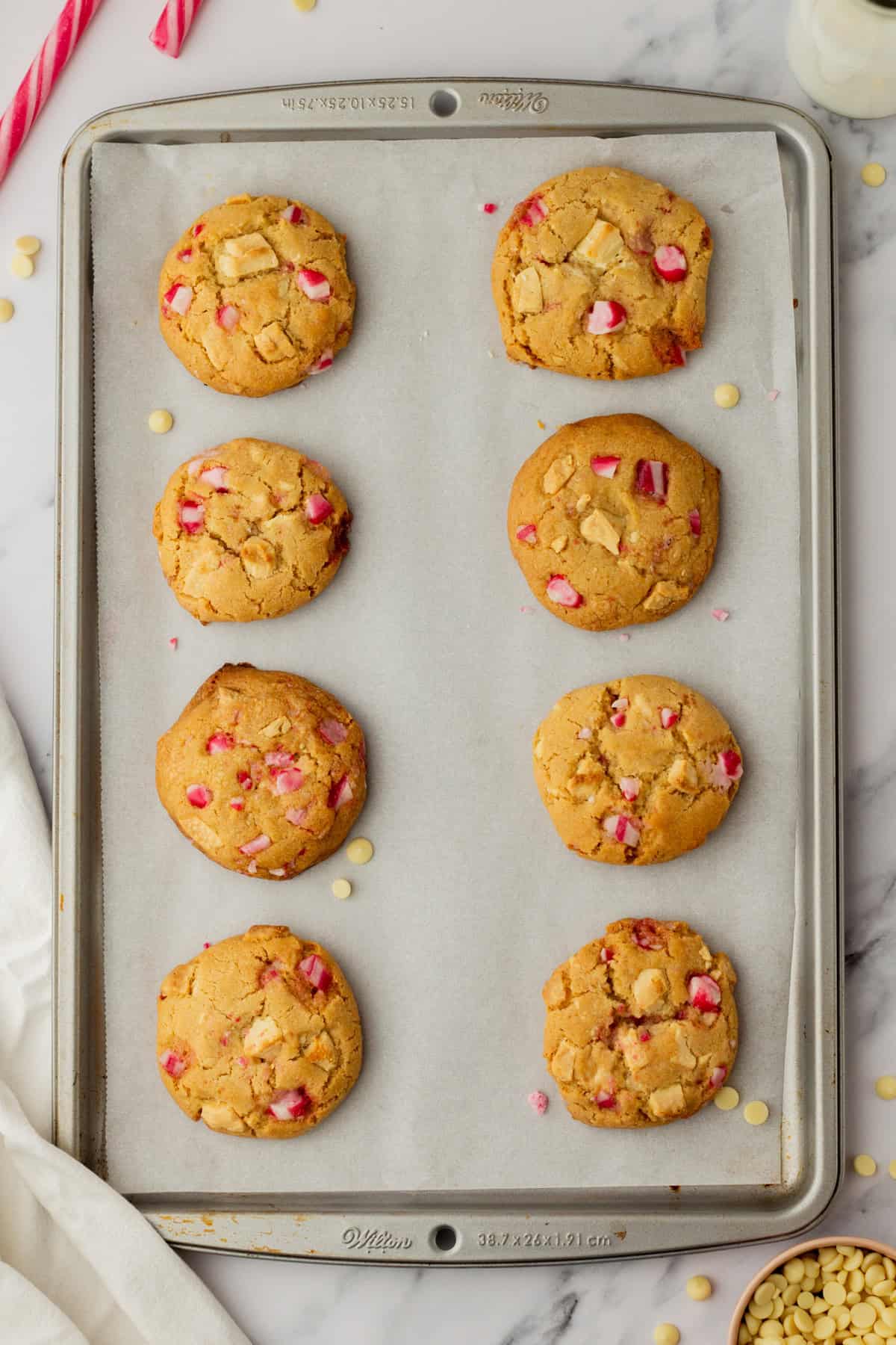 An overhead image of baked white chocolate peppermint cookies on a baking sheet.