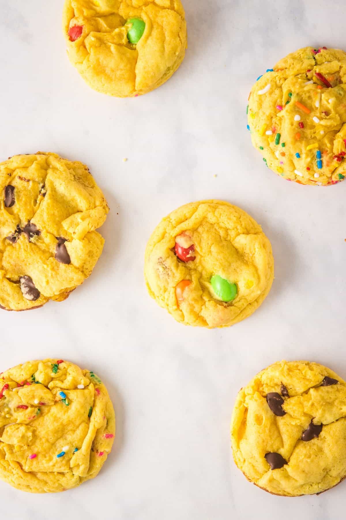 Overhead view of yellow cake mix cookies on a white marble surface.