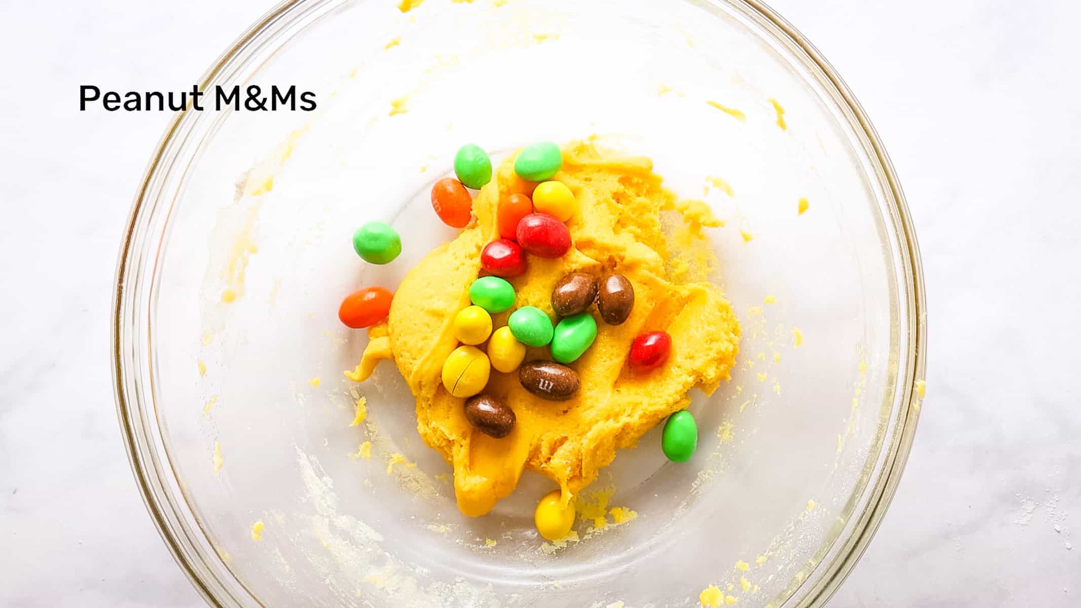 Overhead view of M&Ms into the cookie dough.