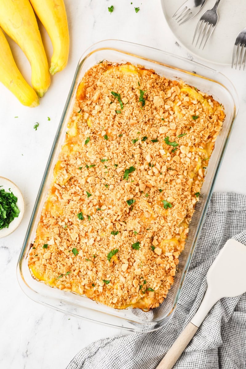 Baked yellow squash casserole with a golden, crispy cracker topping in a glass baking dish.