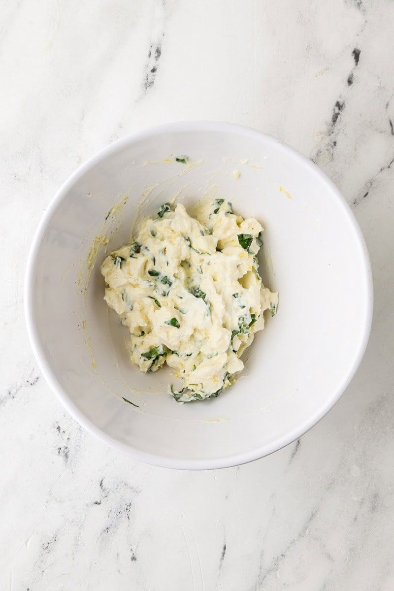 Ricotta filling mixed with mozzarella, basil, and lemon zest in a bowl.