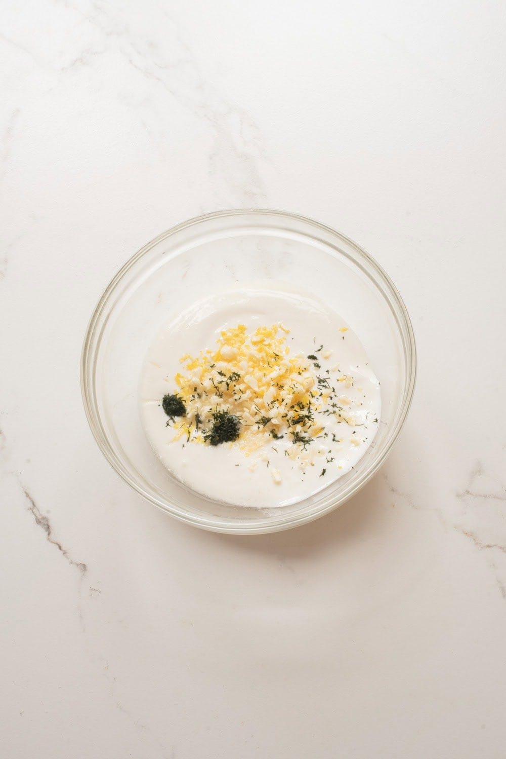 Ingredients for lemon dill yogurt sauce mixed together in a bowl.