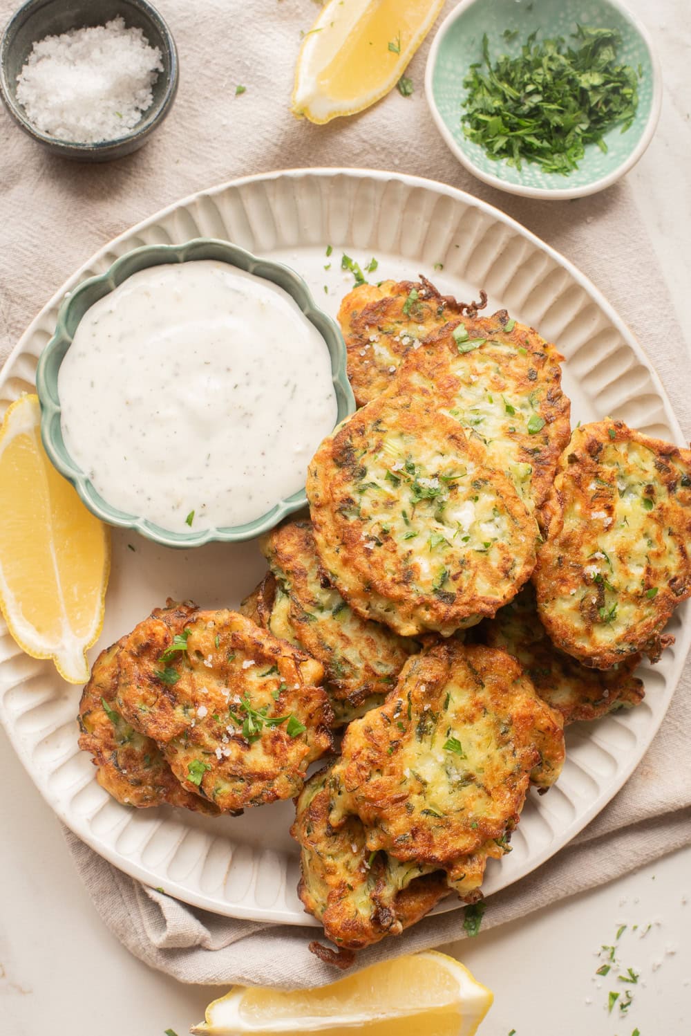 Zucchini fritters served with creamy yogurt sauce and lemon wedges.