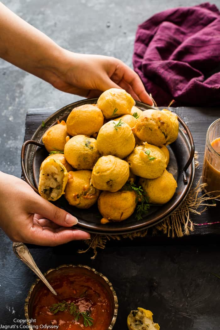 Batata vadas on a platter being placed onto the table, purple napkin in the background.