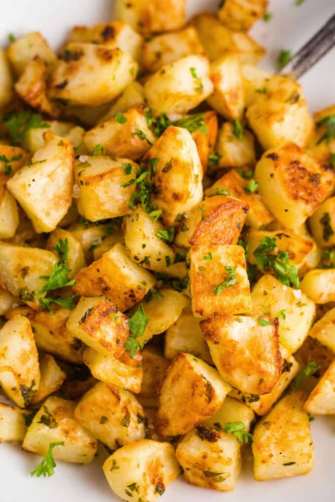 Overhead close-up view of garlic-roasted potatoes with parsley on top. 