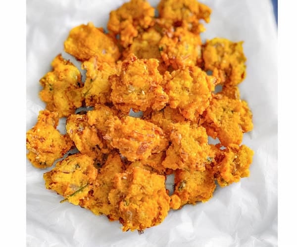 Overhead view of cabbage moong dal pakoda (Moong Lentil Fritters) on a white background.