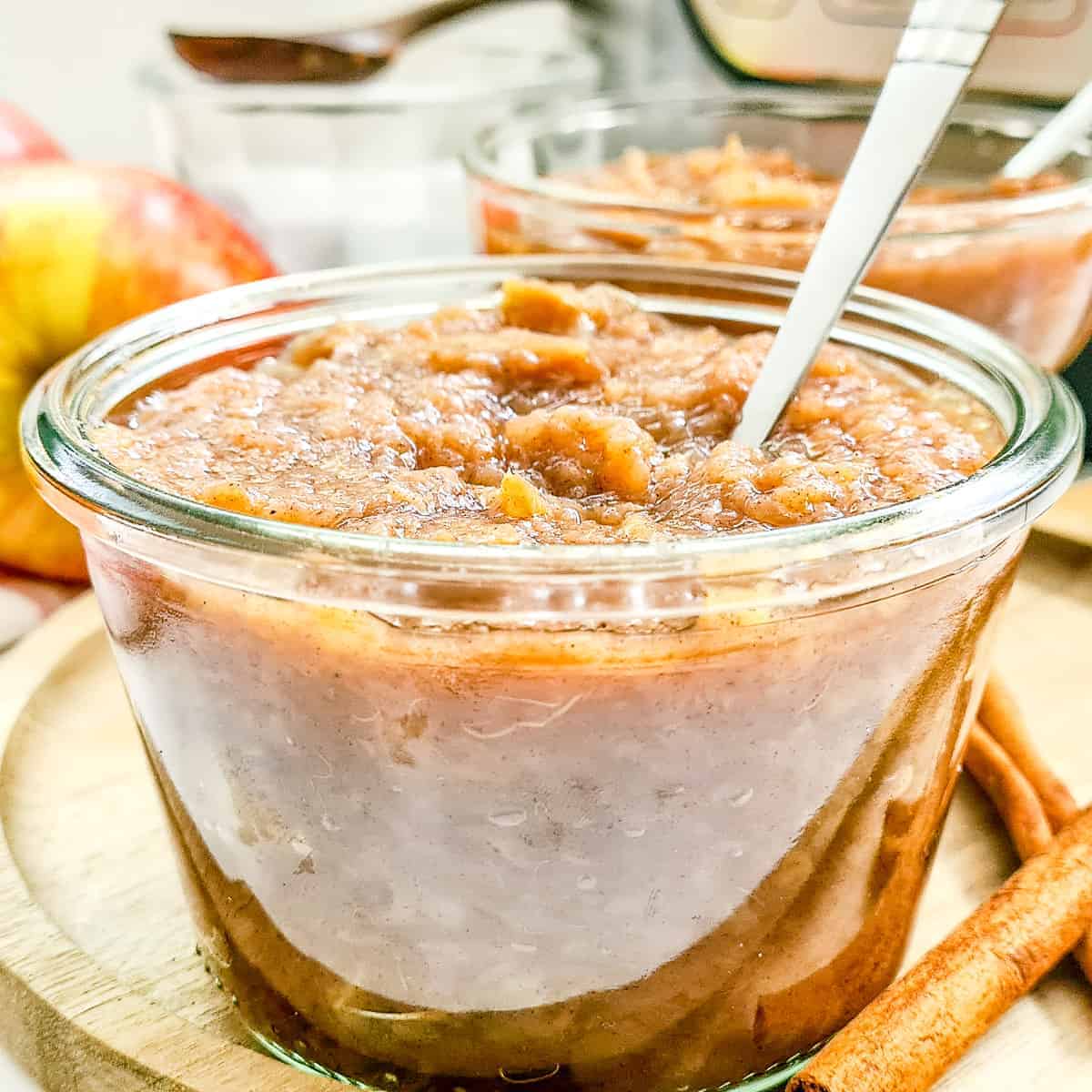 Close up of applesauce in a glass jar with a spoon sticking out.