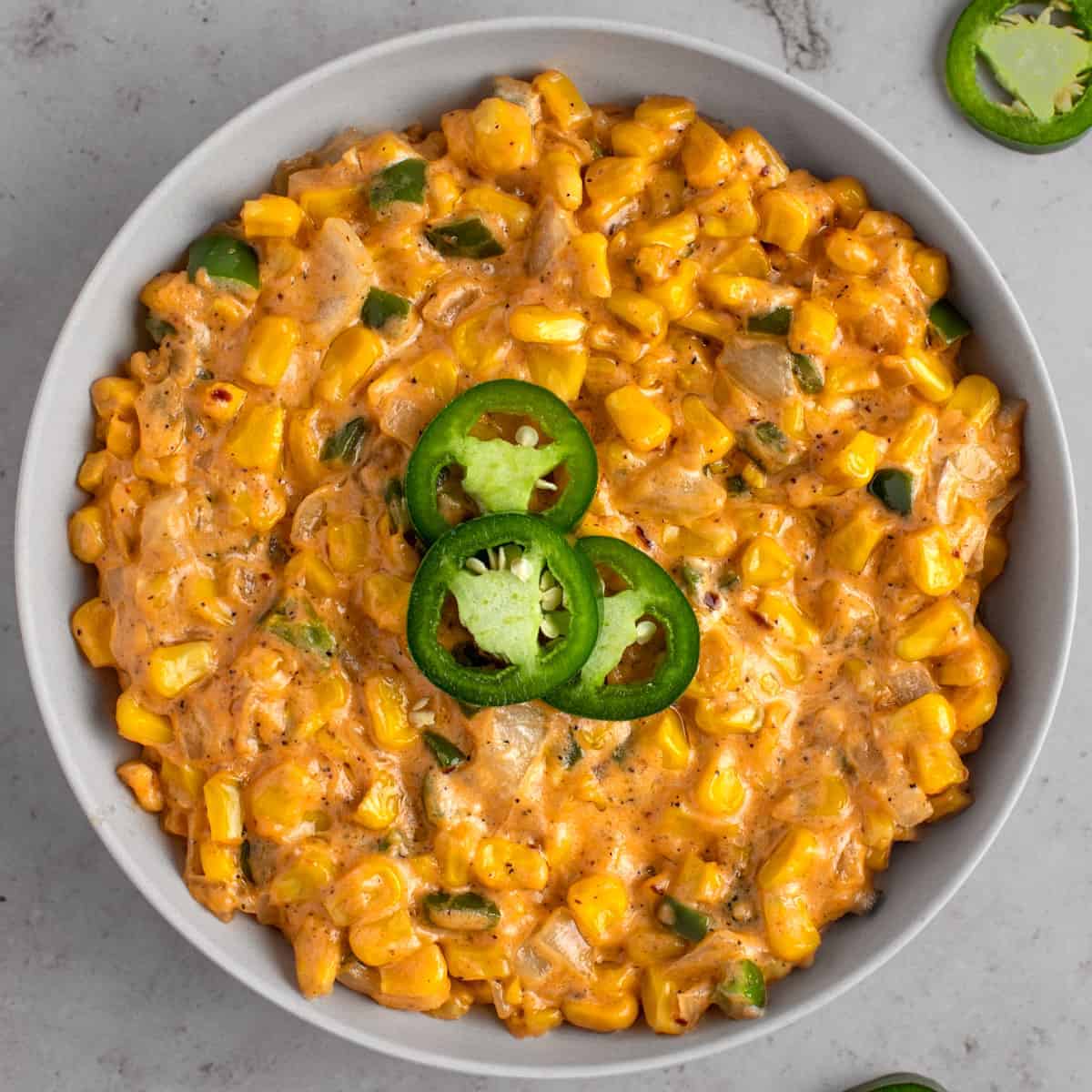Overhead view of creamy jalapeno corn with slices of jalapeno on top.