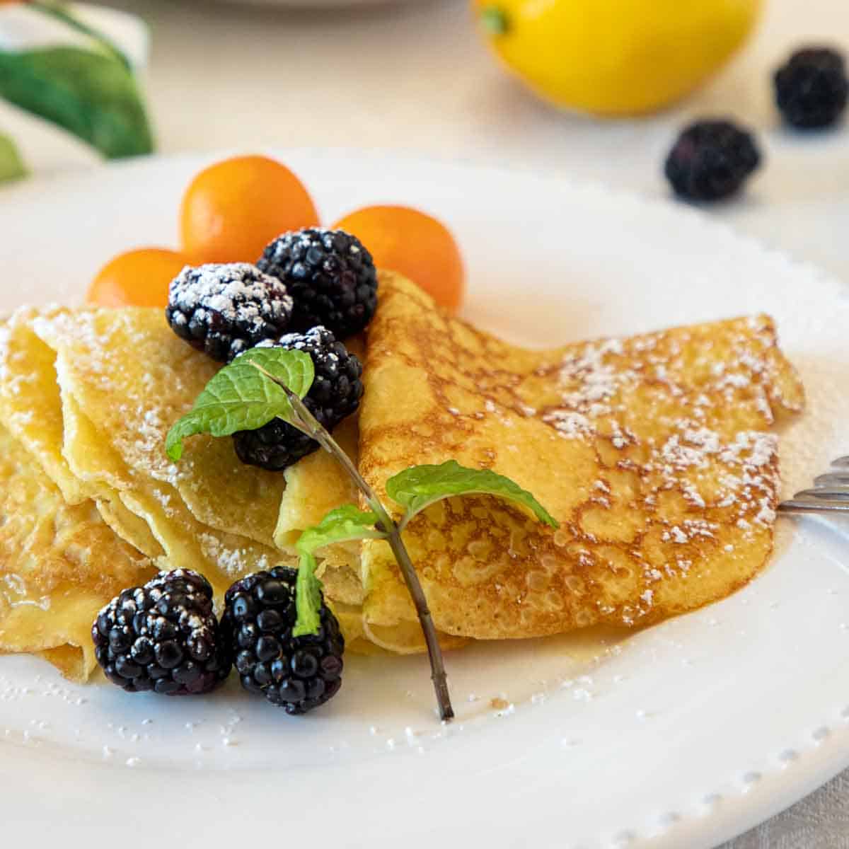 A close-up view of the easiest crepes with lemon curd recipe placed on a white plate.