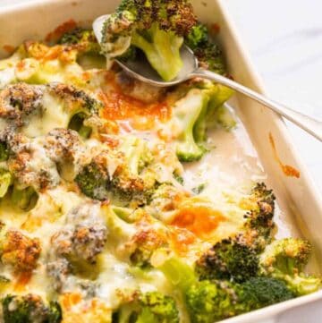A close up image of broccoli cheese casserole with a piece of broccoli on a spoon.