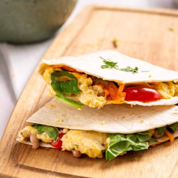 An image of two breakfast quesadillas on a wooden cutting board.