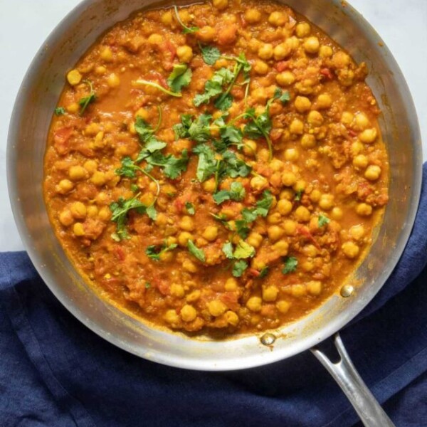 Skillet with chana masala on a blue napkin.
