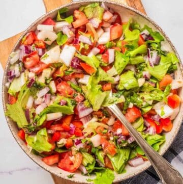 An overhead image of vegan chopped salad in a bowl with a serving spoon in the middle.