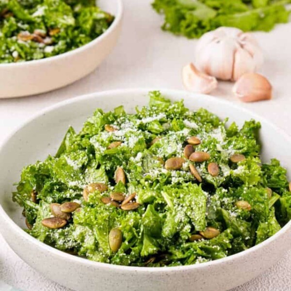 Side angle view of finished salad with white bowl with extra bowls of salad in the background.