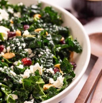 A close up image of kale salad with cranberries and almonds