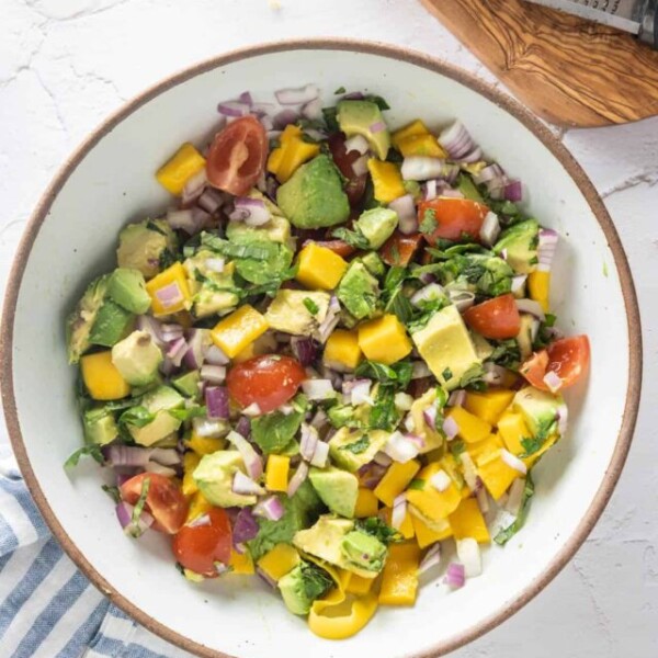 Bowl of finished salad on pinstriped blue napkin, with lemons in the background on wooden platter