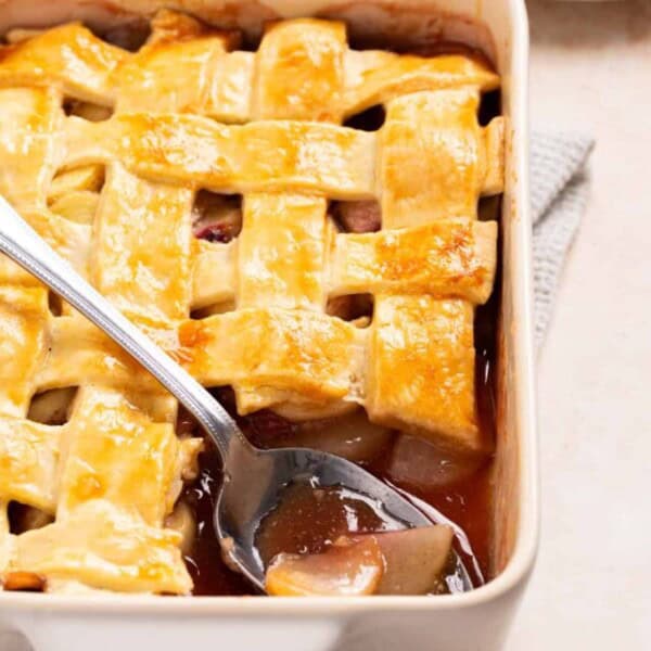 A close up image of peach cobbler with a spoon resting on top.