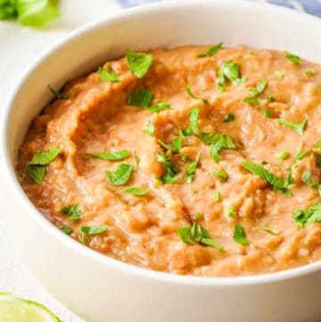 Close up of refried beans in a white bowl, side angle.