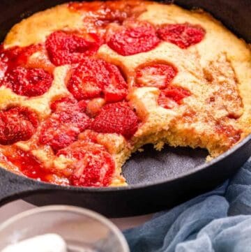 A close up shot of strawberry spoon cake in a cast iron skillet, ready to be served.