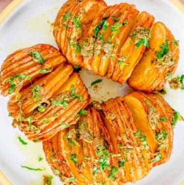 An overhead image of three freshly cooked hasselback potatoes sprinkled with parsley on top.