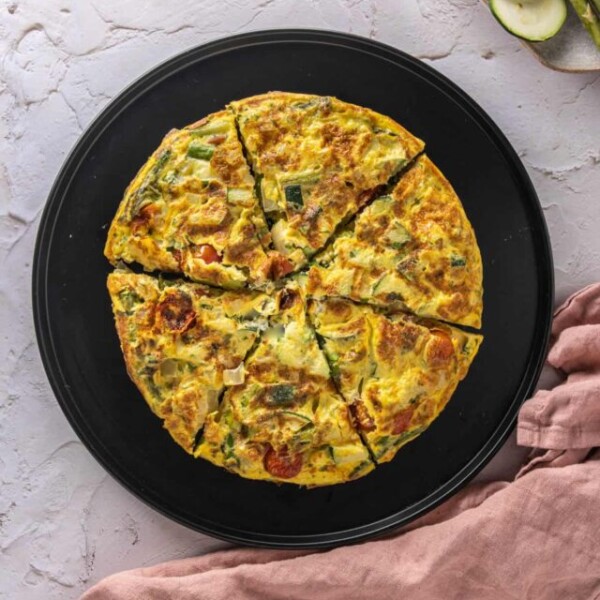 Frittata on a black serving platter with a pink napkin