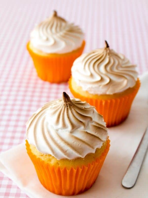 Close up of lemon curd cupcakes with meringue topping in orange cupcake wrapper.
