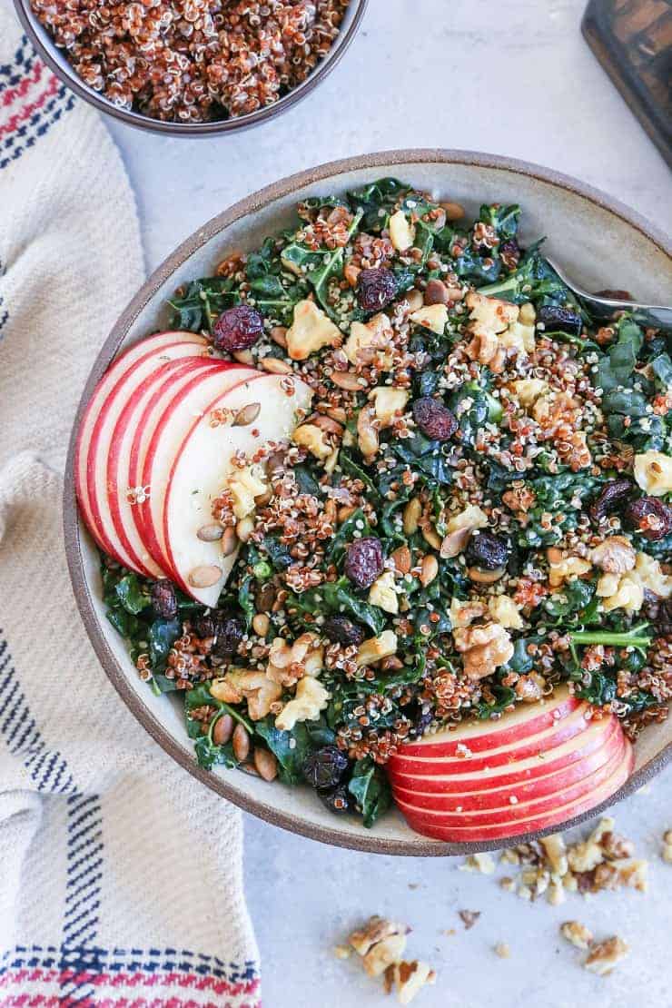Overhead view of a transparent bowl filled with kale apple salad with walnuts and cranberries.