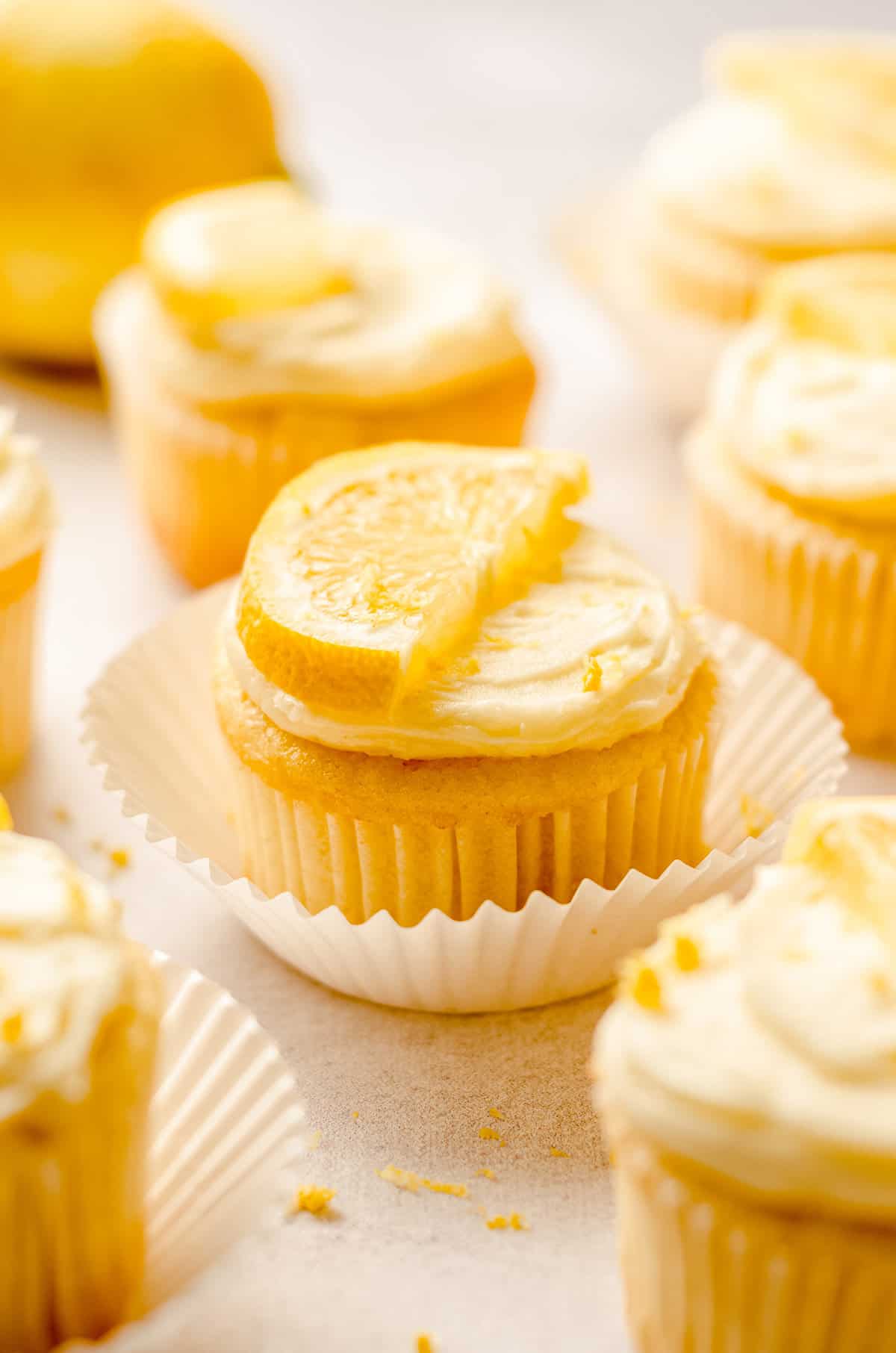 Close up of lemon cupcake with half slice of lemon on top, in white wrapper