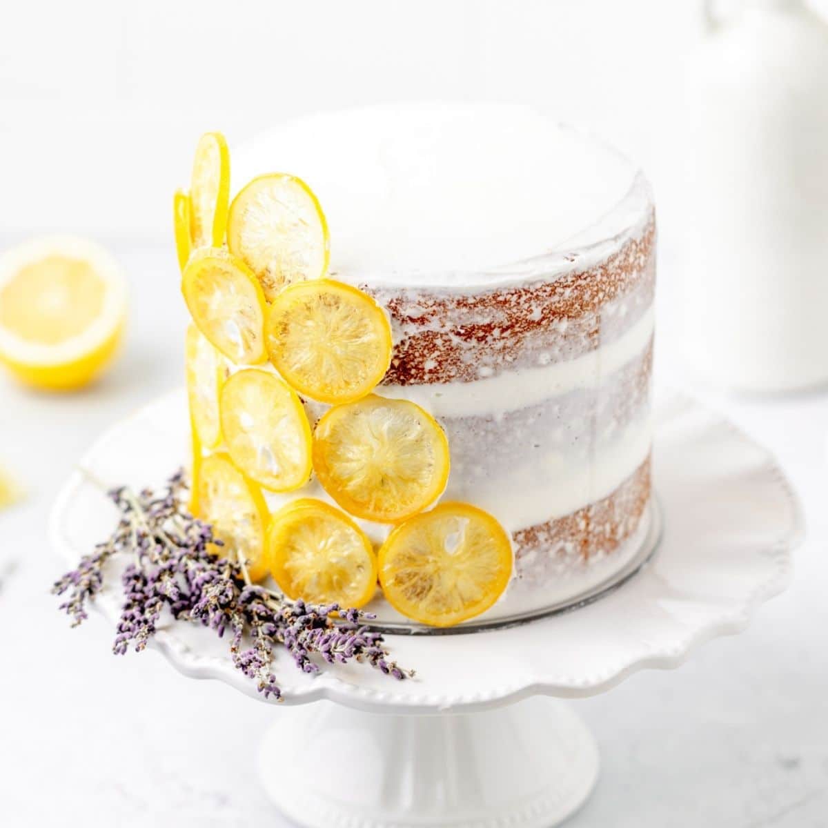 A straight view of a lemon lavender cake with lavender and lemon on the side.