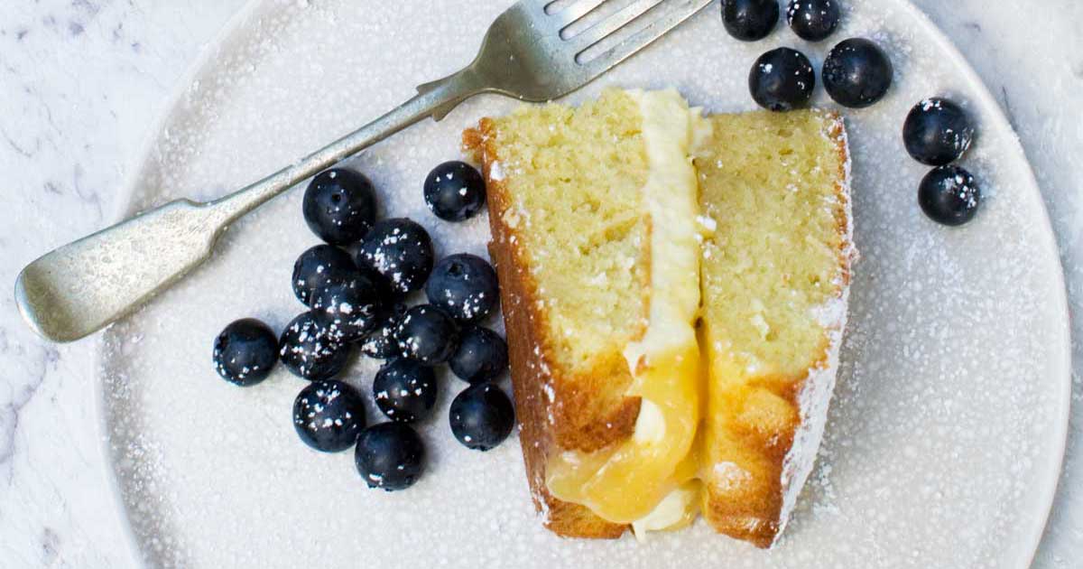 An overhead view of lemon mascarpone cake with blueberries and a fork placed on a plate.
