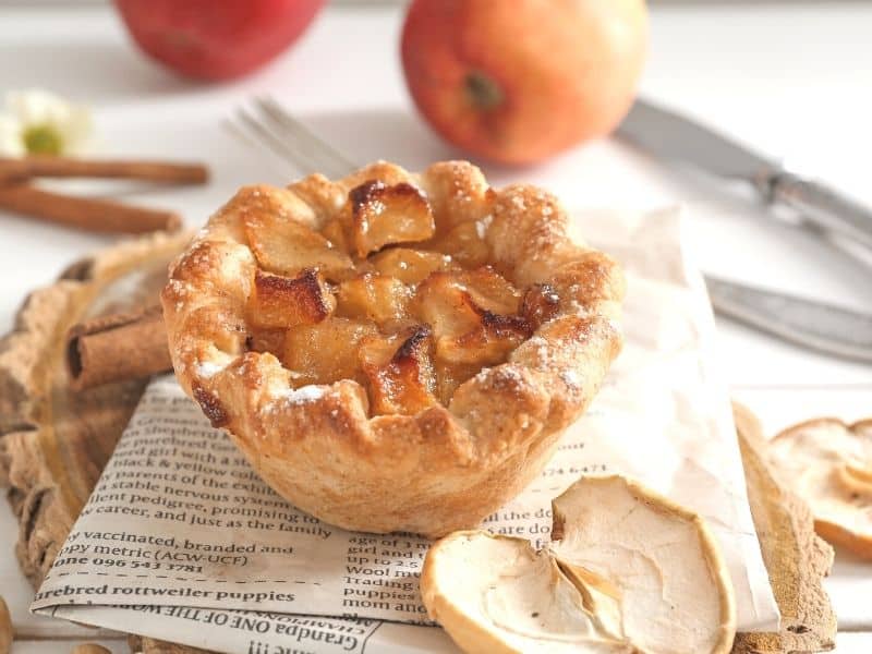 Mini apple pies made with short crust, placed on newspaper.