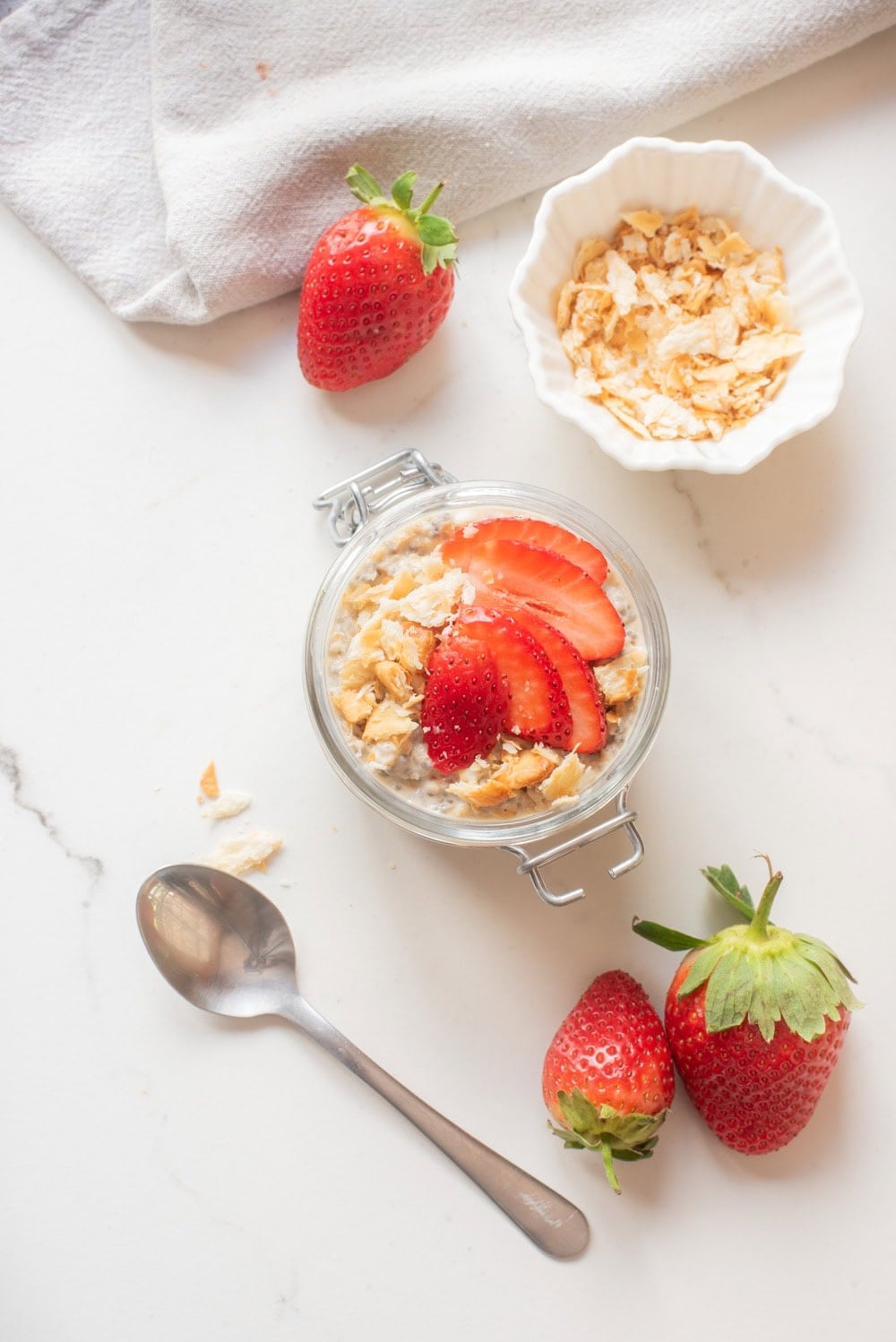 Strawberry cheesecake overnight oats topped with sliced strawberries and graham cracker crumbs.
