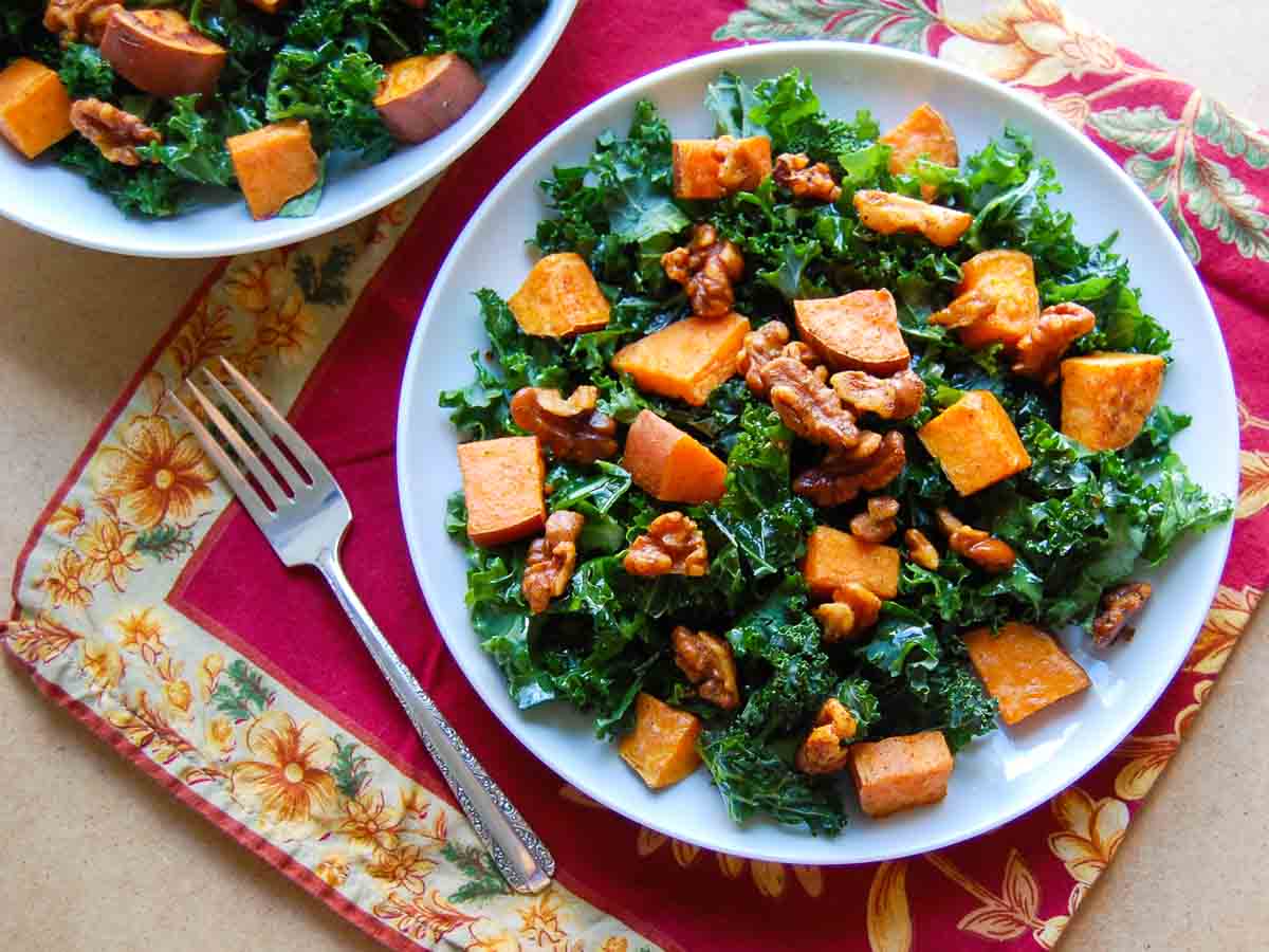 Overhead view of roasted sweet potato kale salad on a white plate with a fork next to it.